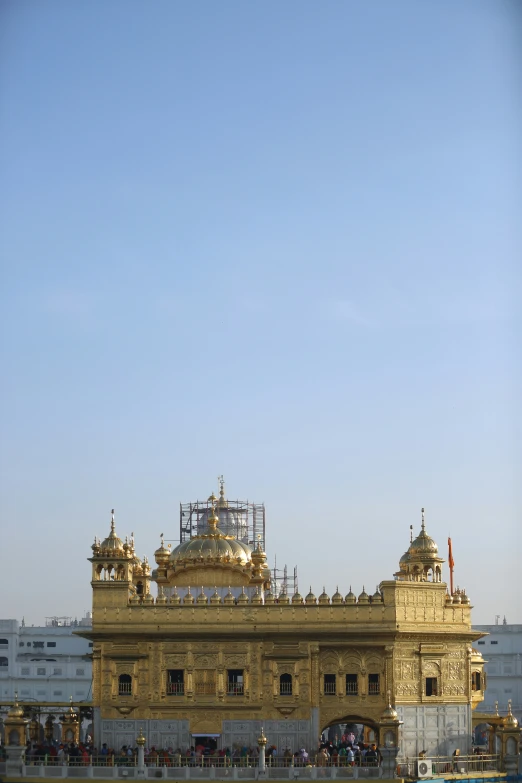 a very big building on the water with a lot of people around it