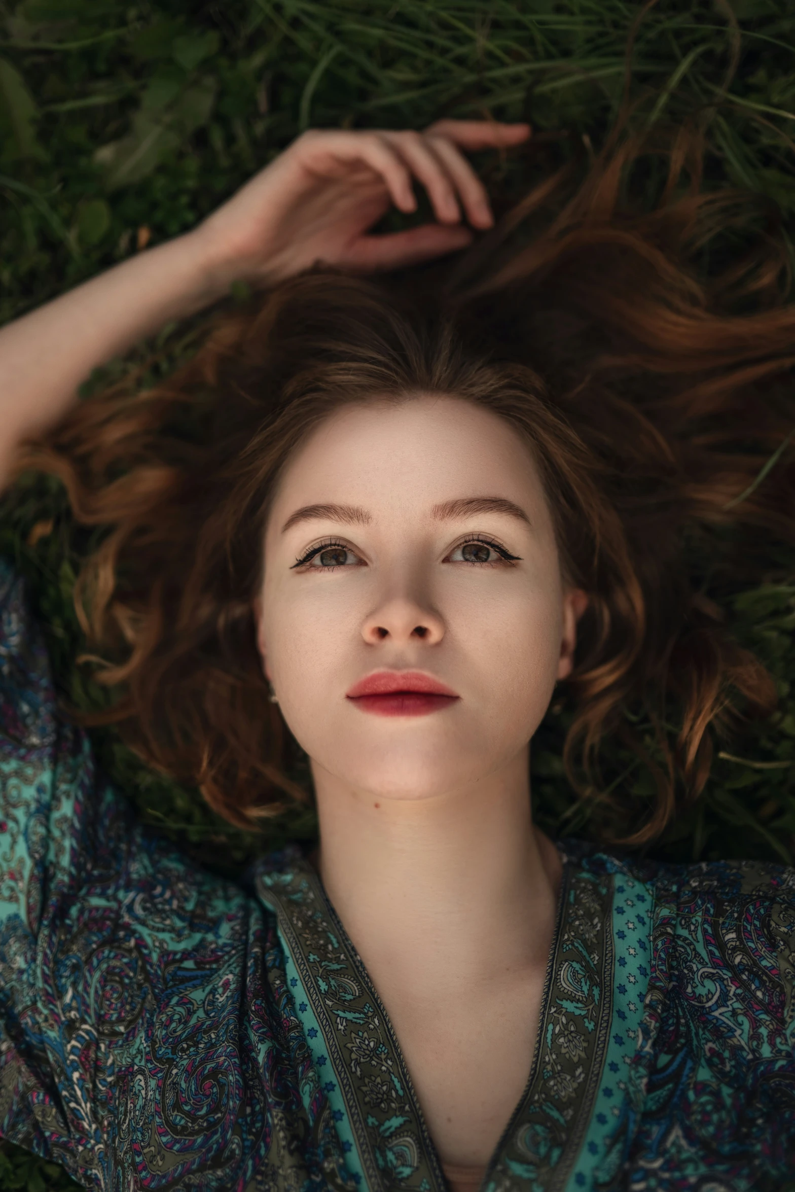 young woman laying on the grass with her hair in air