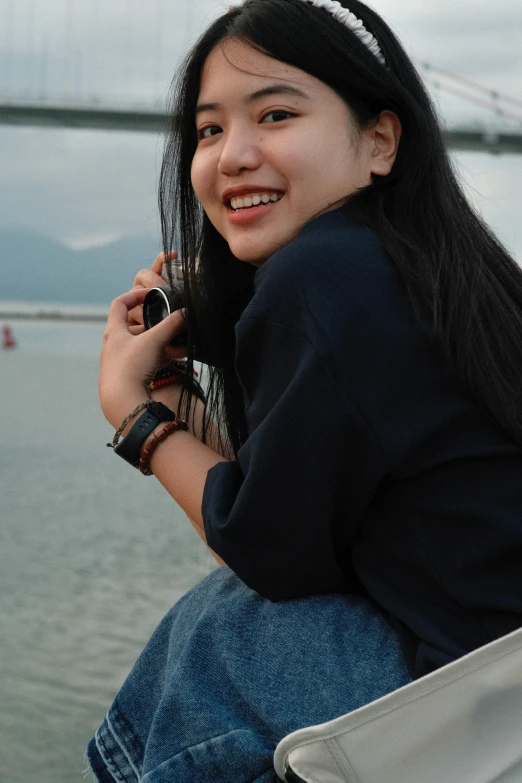 a young woman is sitting with a cell phone