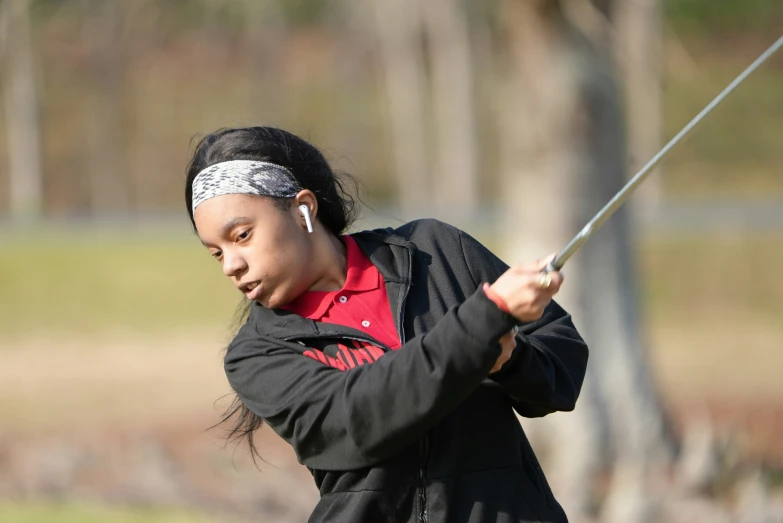 a woman is in the field swinging a golf club