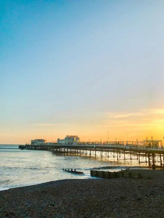 the sun sets behind the pier and the water is crystal blue