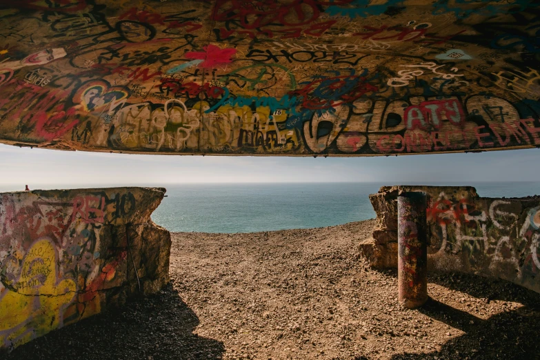 some graffiti is painted on a concrete wall over the ocean