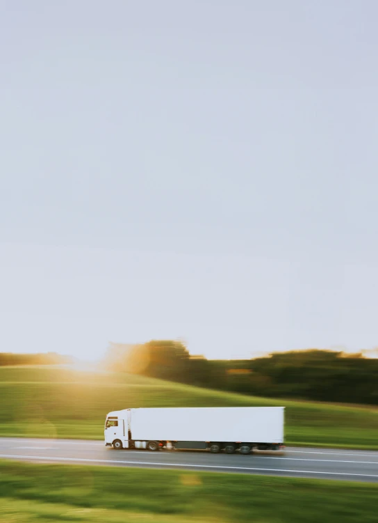 a semi truck drives on a highway near a field