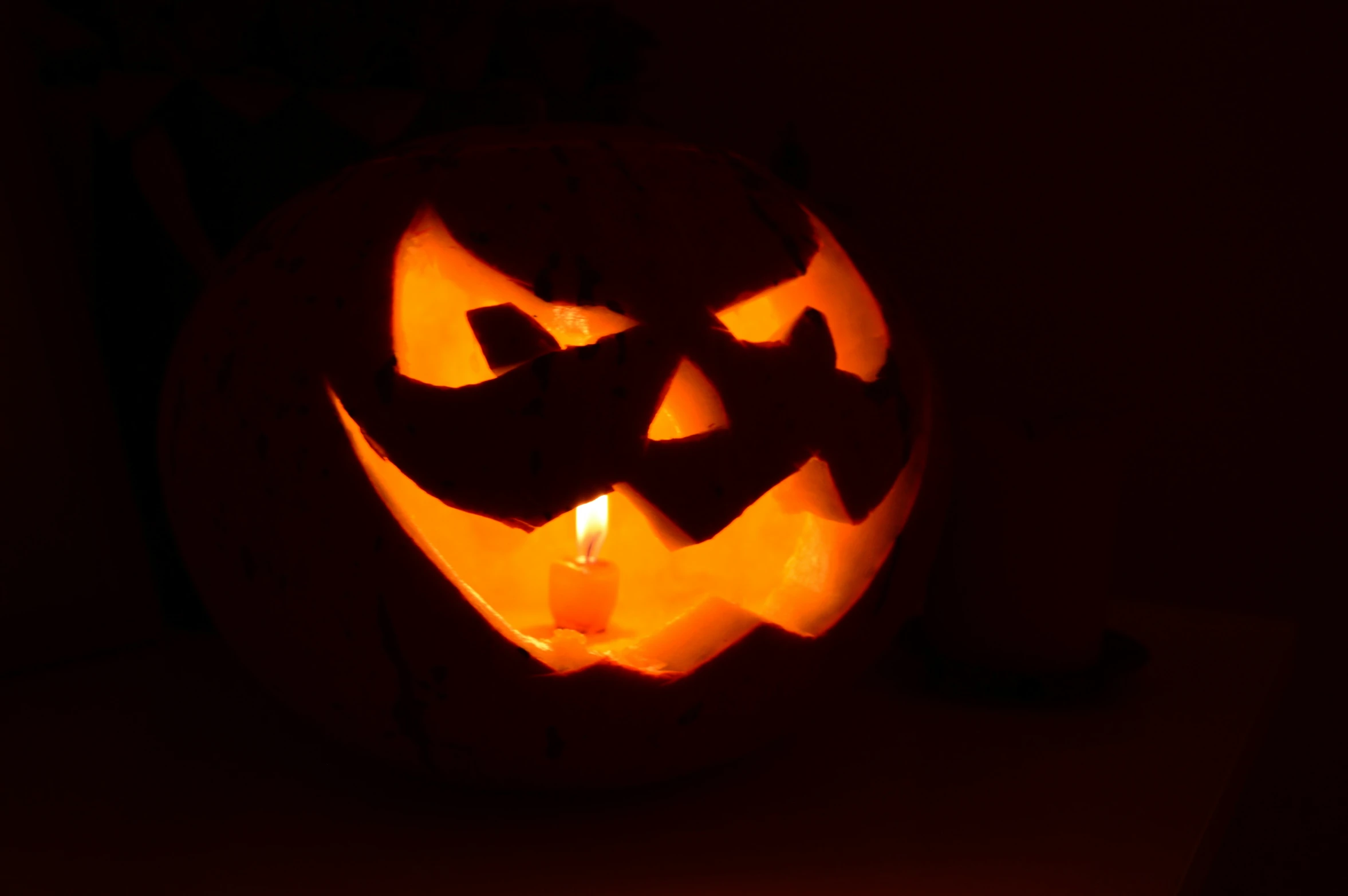 a lit up pumpkin with cut out mouth and eye