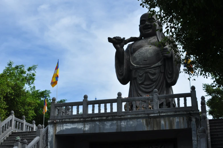 a big statue in front of a bridge with two flags