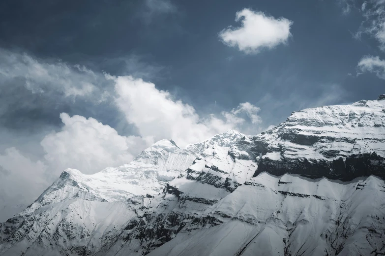 a snowy mountain in the distance with clouds in the sky