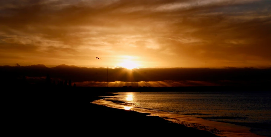 the sun is peeking through some clouds over a beach