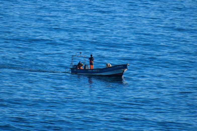 a small boat with two people in it floating on a body of water