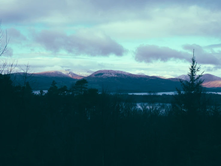 the view of the mountains and a lake under cloudy skies