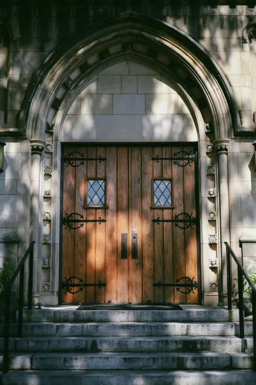 two wooden doors are near the steps of a church