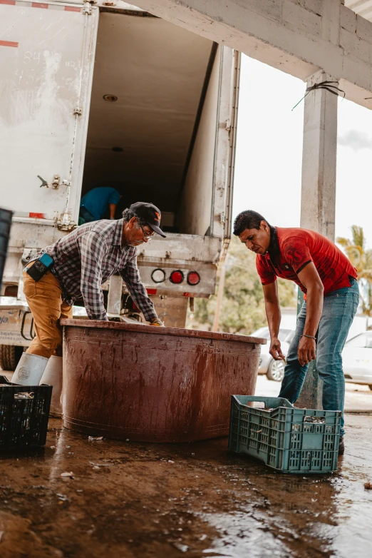 two men standing in the mud working on soing