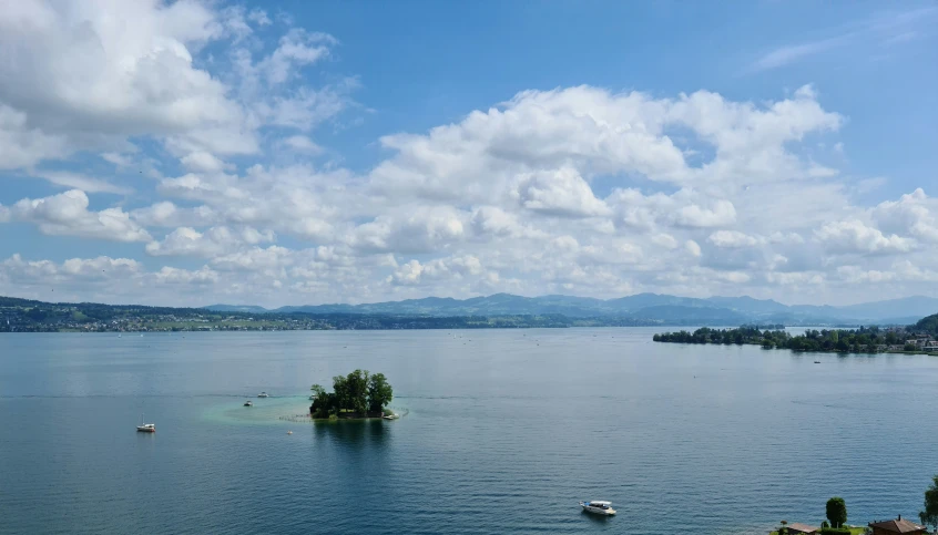 a lake with boats on it in the middle of a sky with clouds