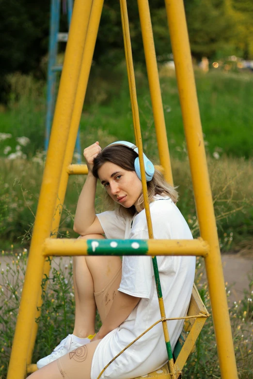 a girl sits on the swing with headphones on