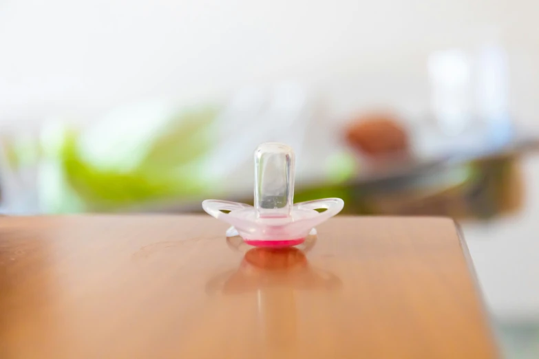 an adorable pink pacifier is on a small wooden table