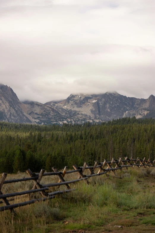 a fence sits in the middle of a field with mountains in the background