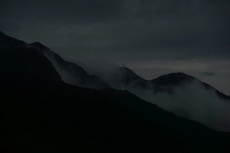 there are dark mountains that appear to be shroud by clouds