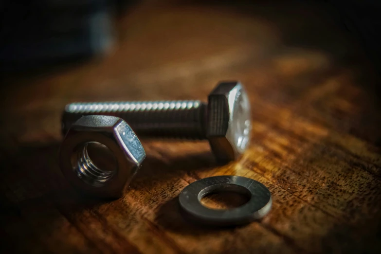 three small screws and one nut on a wooden table