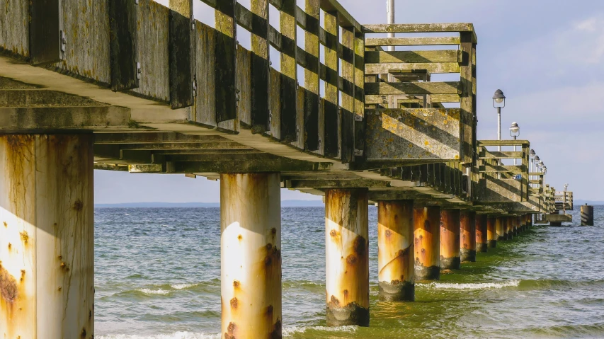 a pier overlooking the ocean with a blue sky and some brown columns