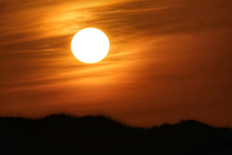 a po of the sun setting over a hill