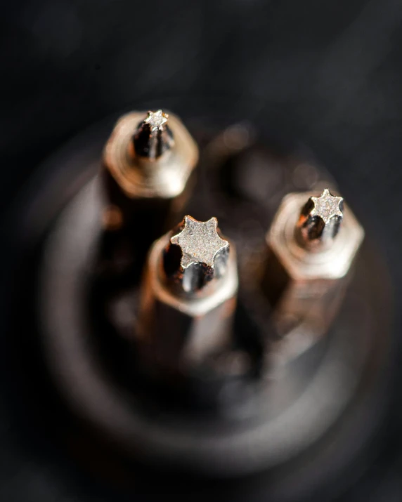 four shiny gold diamond shaped objects on a black table