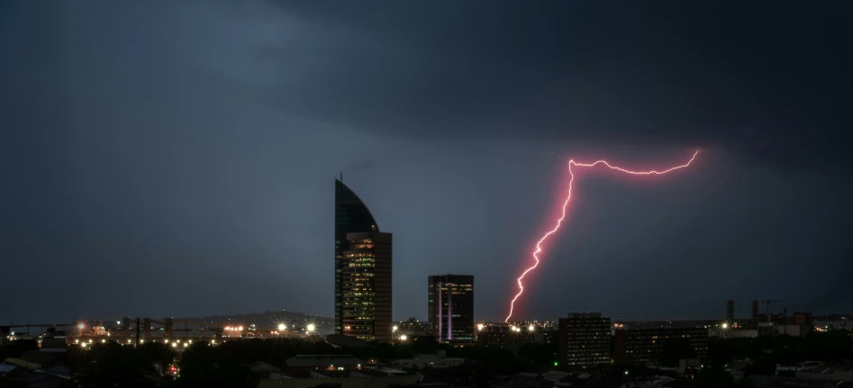 a lightning bolt appears over a city in a cloudy sky