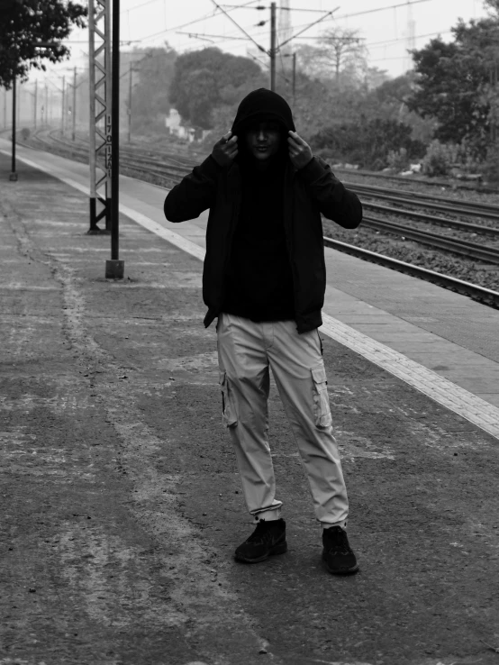 black and white pograph of a young man standing at a train platform