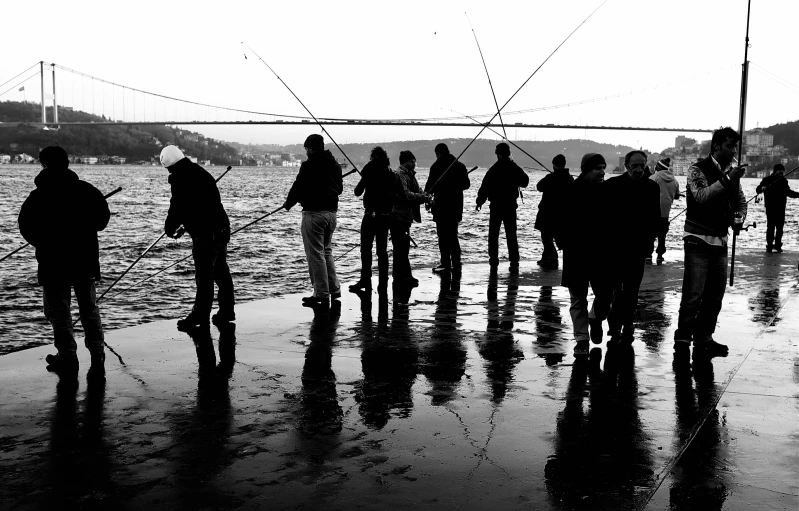 many people standing on a beach looking at the water