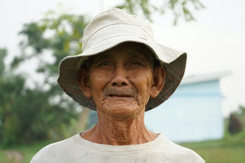 an old man in white shirt and hat in grassy area