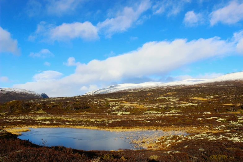 the blue sky is covered with clouds as the mountains sit in the distance