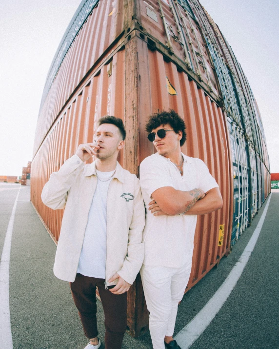 two guys standing on a dock next to a large orange structure