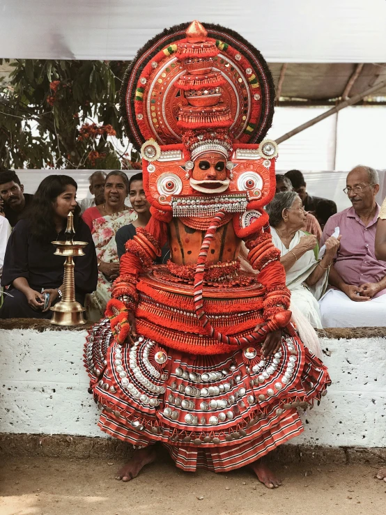 an african man dressed in traditional garb holding a silver chalicee