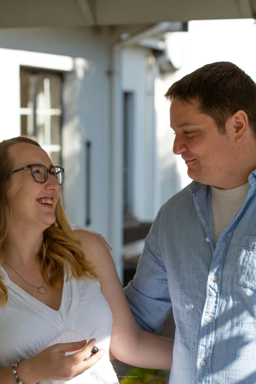 a man in glasses standing next to a pregnant woman