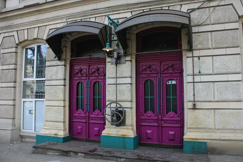 two pink double doors on a building with a lamp on top of it