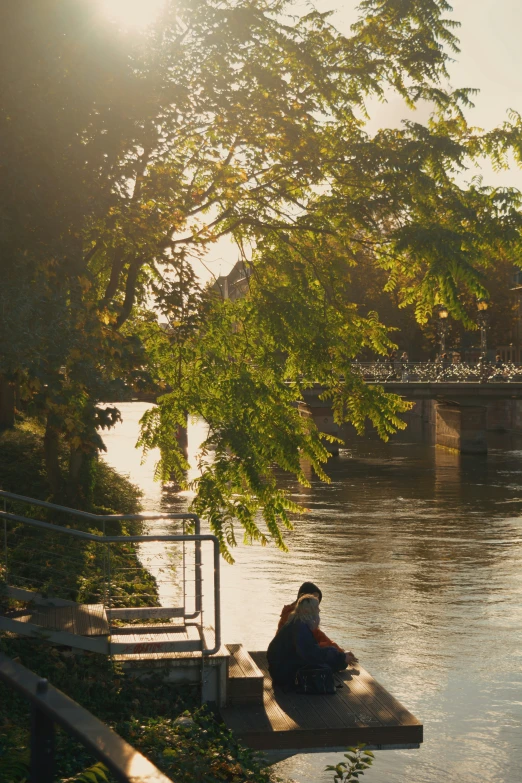 a person is sitting on the pier by the water