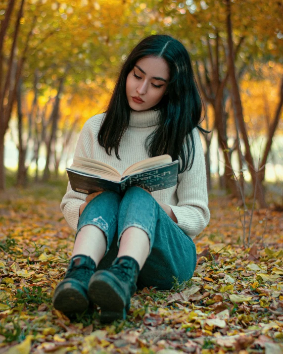 a girl sitting on the ground reading a book