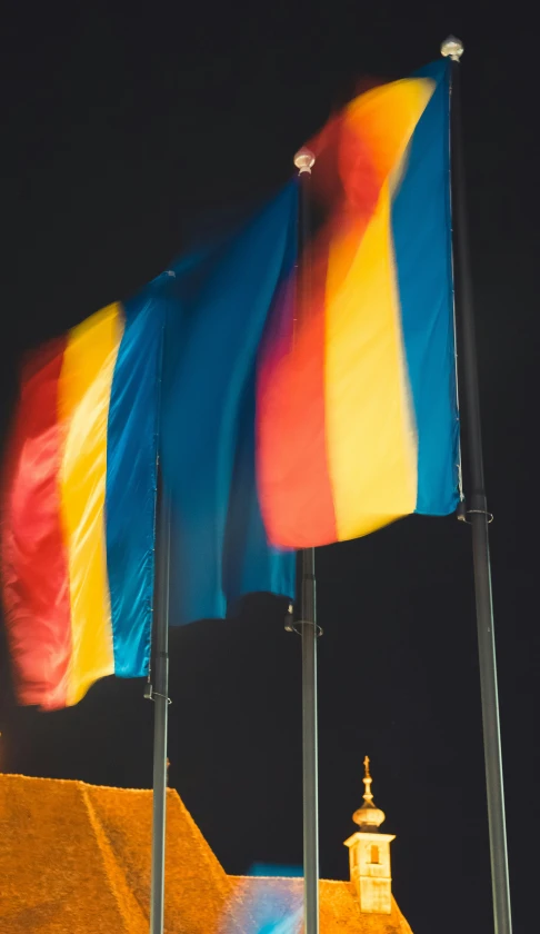 a rainbow flag flying next to another colorful flag