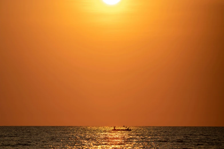 a boat out in the ocean as the sun sets