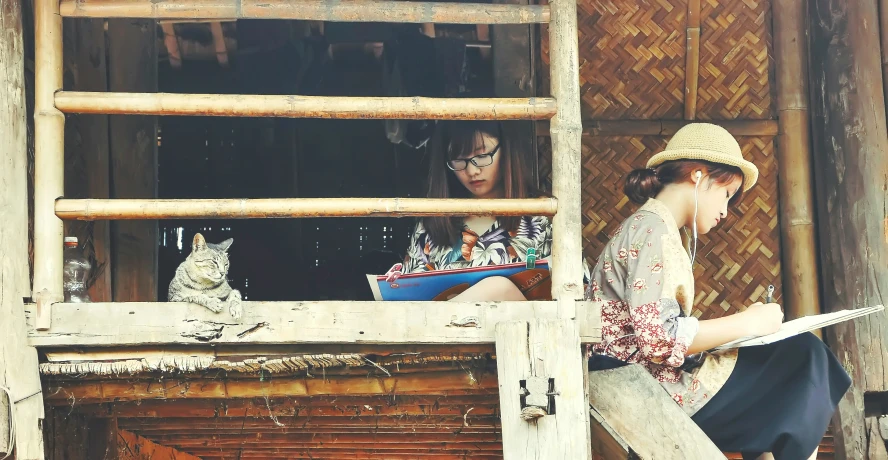 two young people standing outside of a hut