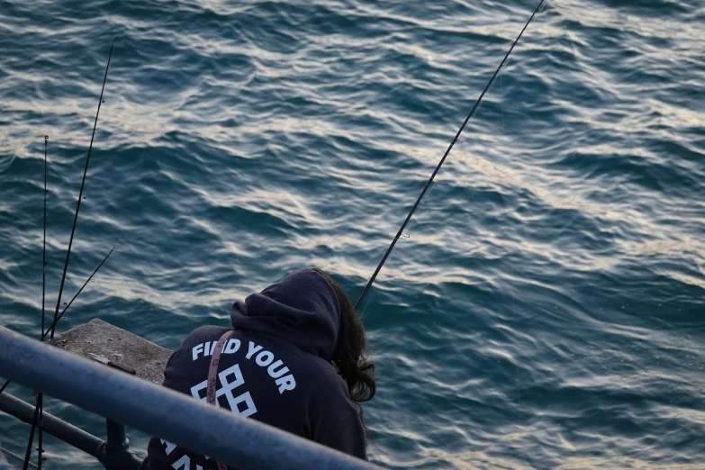 someone sitting at the railing fishing on water