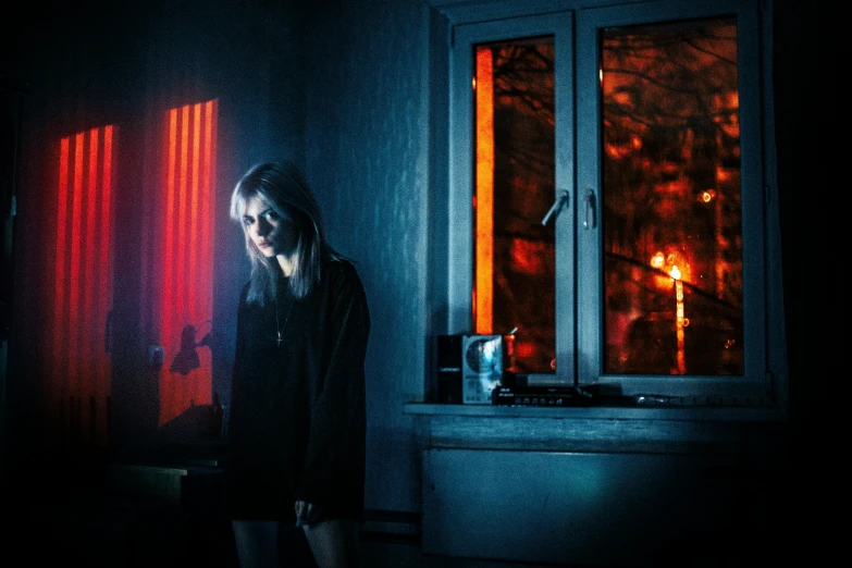 a woman standing in front of a window at night