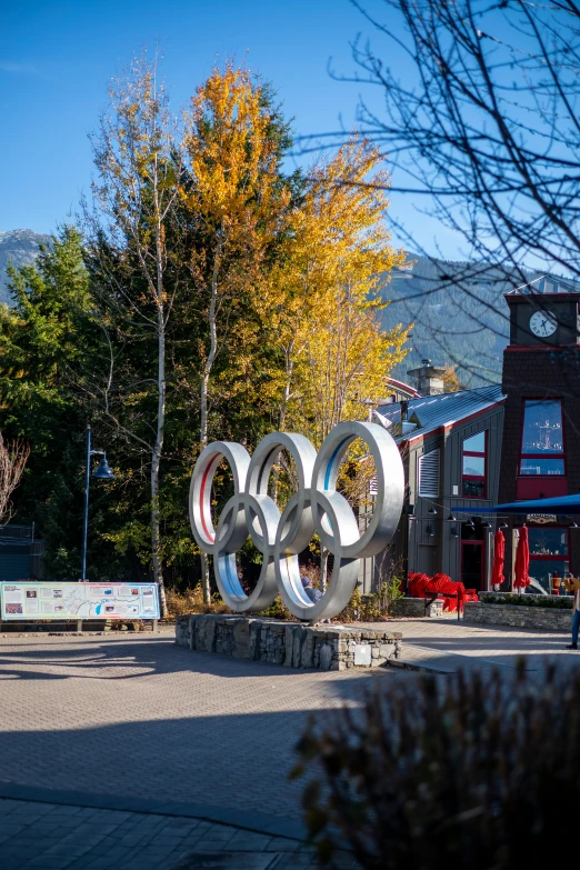 a giant olympic symbol made from metal rings sits on the curb of an urban area
