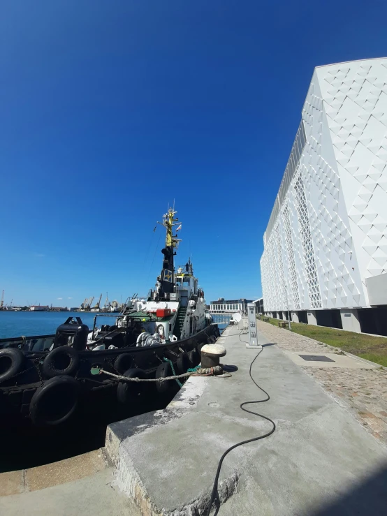 a tug boat parked beside an industrial building