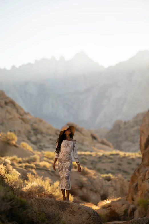 a woman is walking in the hills towards a cliff