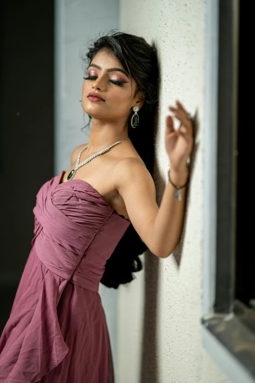 a woman wearing a dress and earrings leaning against the wall