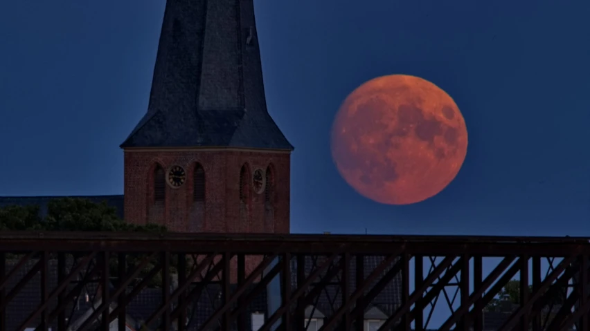 the full moon seen over an old church tower