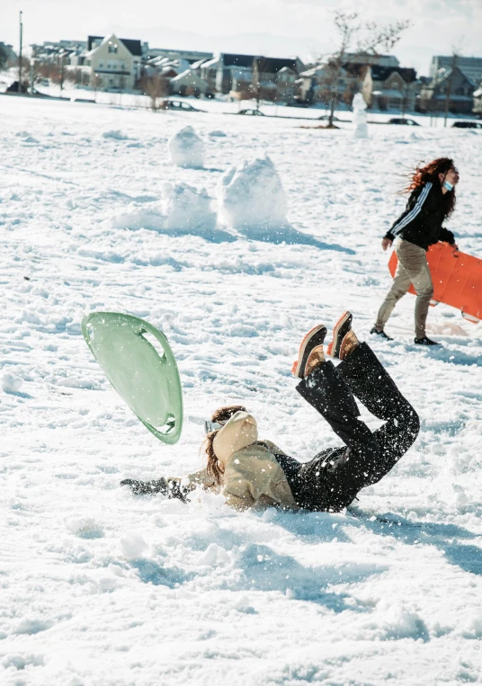 people play frisbee in the snow with houses and buildings