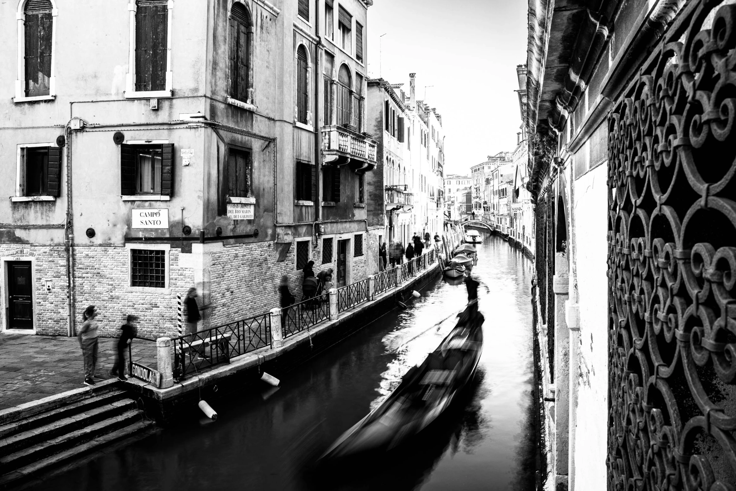 the black and white image of a gondola passing down a canal