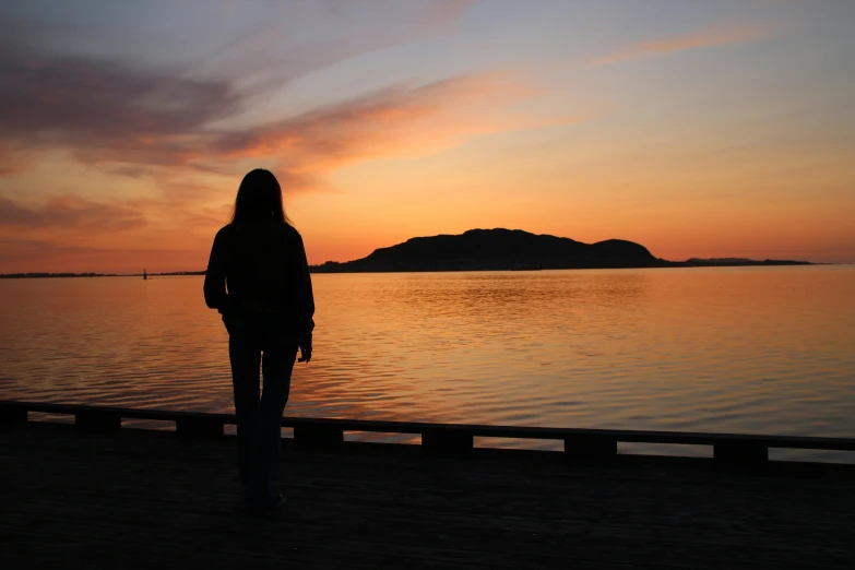 a silhouette of a woman looking into a water