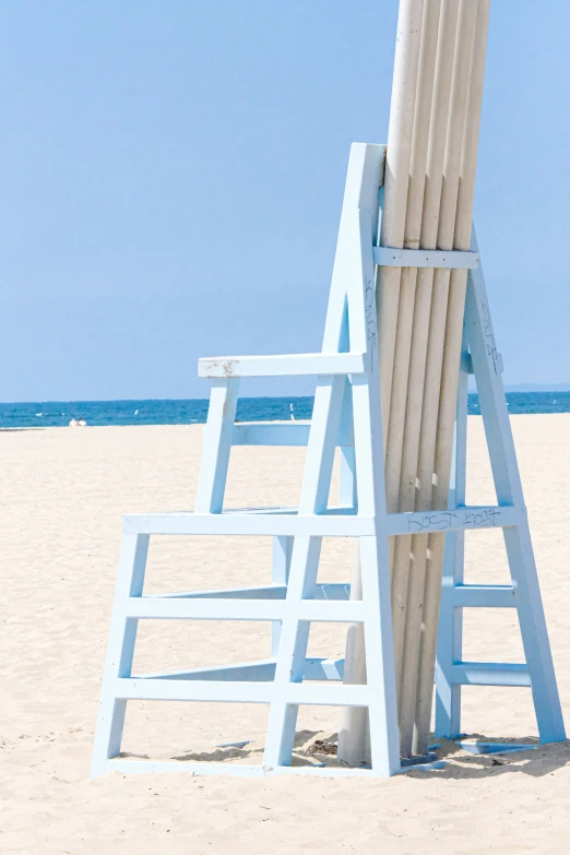 a ladder and chair sitting on a beach in the sand