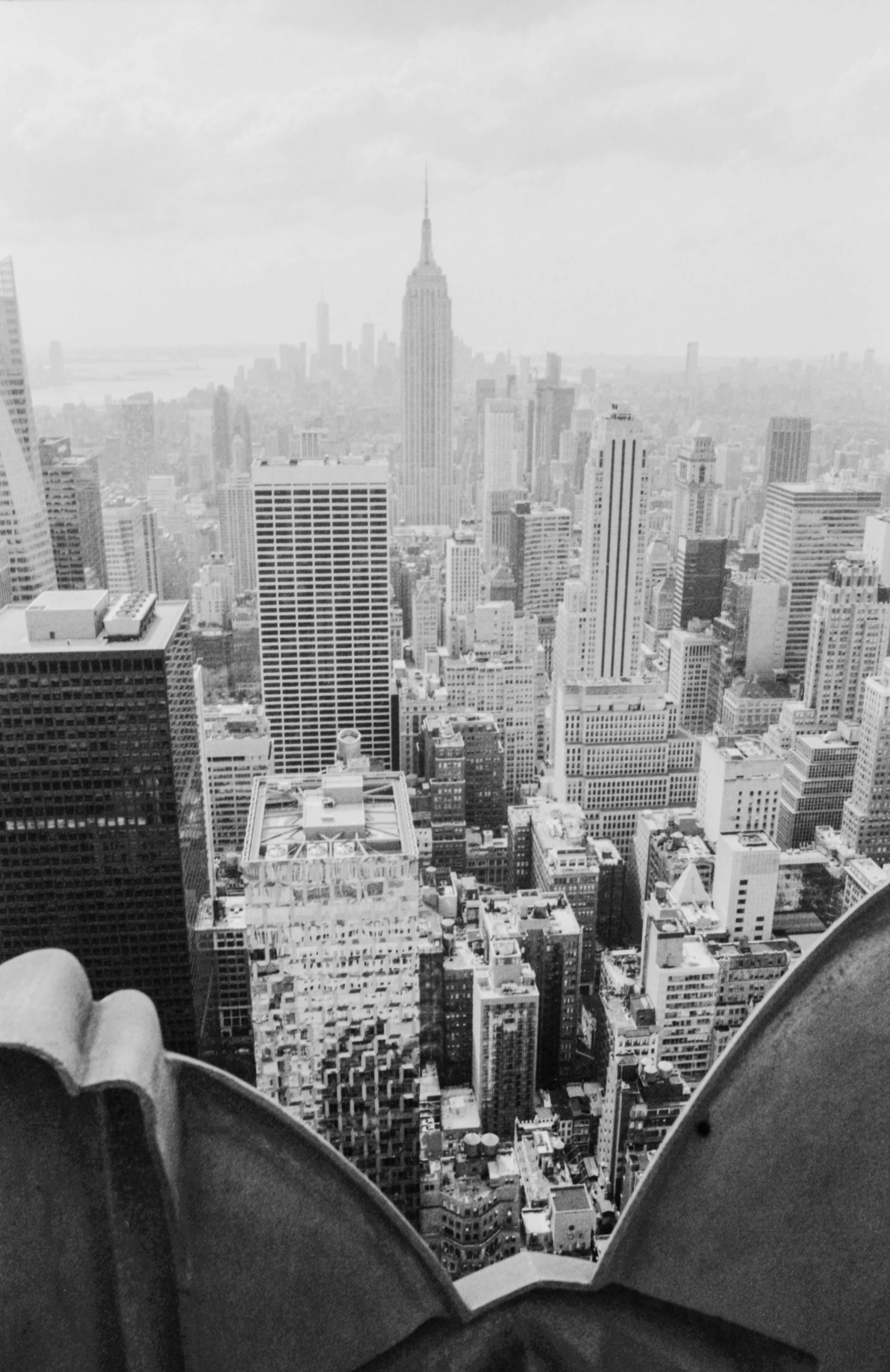 two people sitting on a ledge looking at cityscape